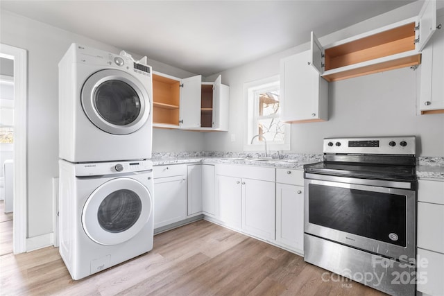 laundry room with laundry area, stacked washer and clothes dryer, light wood finished floors, and a sink