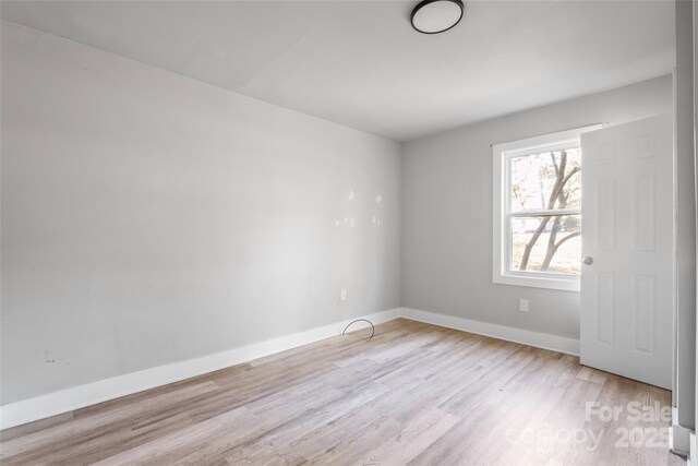 spare room featuring baseboards and light wood finished floors