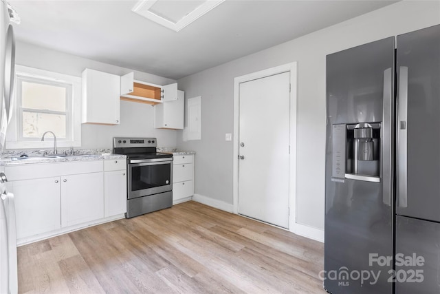 kitchen featuring baseboards, light wood finished floors, a sink, stainless steel appliances, and white cabinets