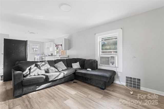 living area featuring visible vents, light wood-style flooring, cooling unit, and baseboards