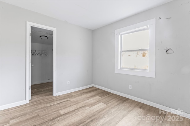 unfurnished room with light wood-type flooring and baseboards