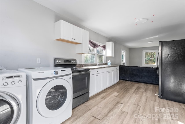 laundry area with light wood finished floors, laundry area, washer and dryer, and plenty of natural light