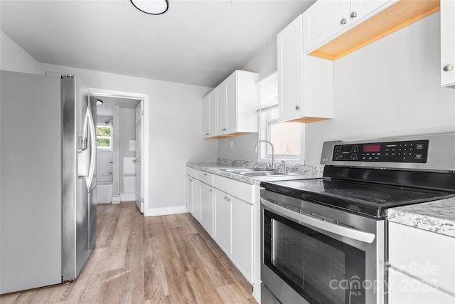 kitchen featuring light wood finished floors, a sink, appliances with stainless steel finishes, white cabinets, and light countertops