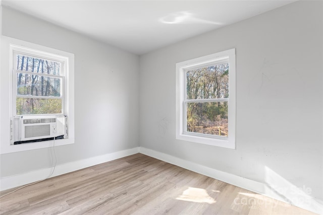 empty room with cooling unit, baseboards, and wood finished floors