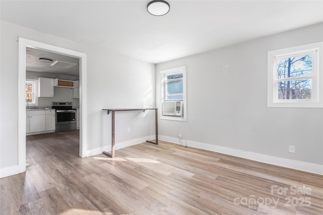 interior space featuring cooling unit, light wood-type flooring, and baseboards