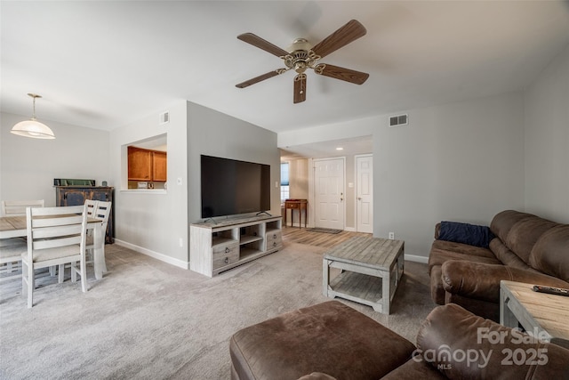 living room with visible vents, light colored carpet, baseboards, and ceiling fan