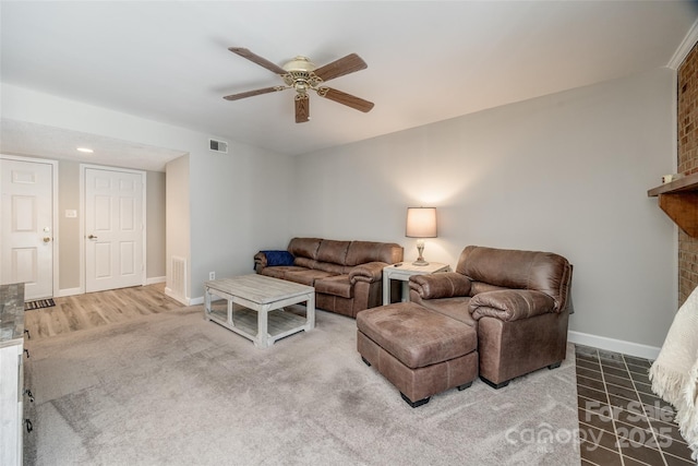 living room with a ceiling fan, a brick fireplace, baseboards, and visible vents