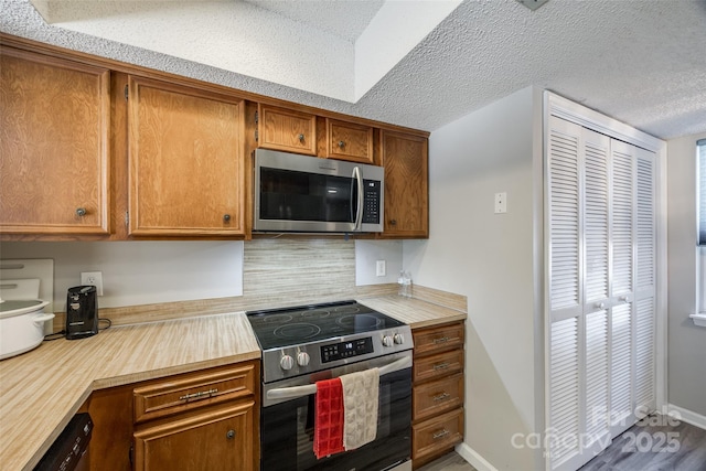 kitchen featuring brown cabinets, a textured ceiling, appliances with stainless steel finishes, and light countertops