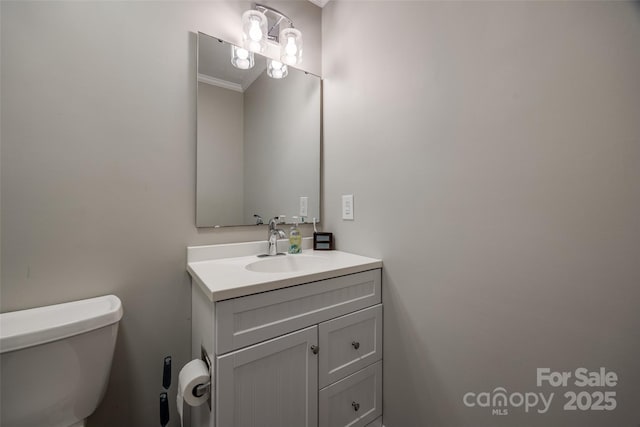 half bath featuring toilet, vanity, and crown molding