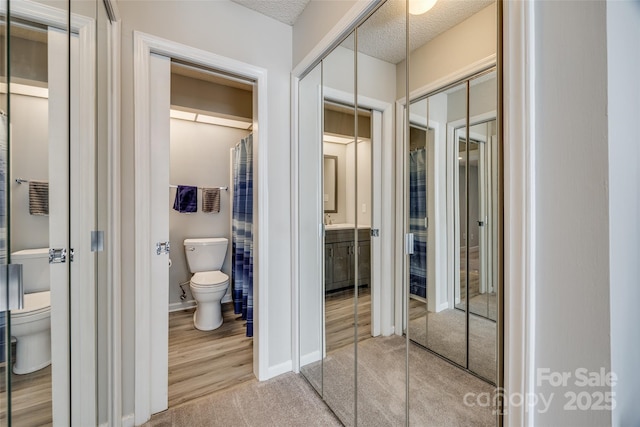 bathroom with toilet, baseboards, and a textured ceiling