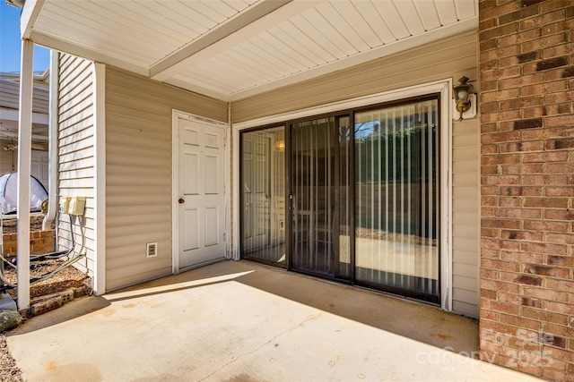 doorway to property featuring brick siding and a patio