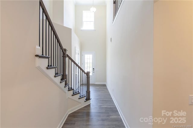 foyer with a towering ceiling, baseboards, dark wood finished floors, and stairs