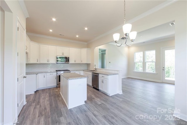 kitchen featuring a notable chandelier, appliances with stainless steel finishes, crown molding, and decorative backsplash