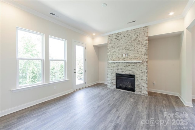 unfurnished living room featuring baseboards, wood finished floors, visible vents, and ornamental molding