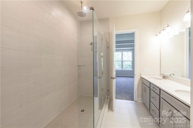 bathroom with tile patterned flooring, double vanity, tiled shower, and a sink