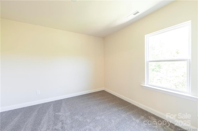 spare room featuring carpet flooring, visible vents, and baseboards