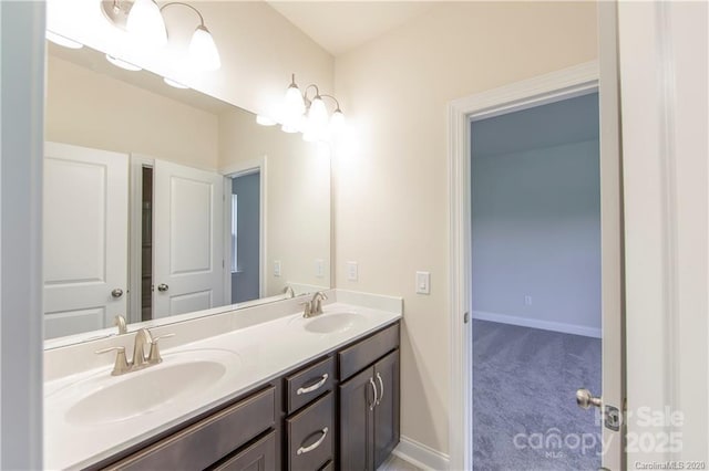 bathroom with double vanity, baseboards, and a sink