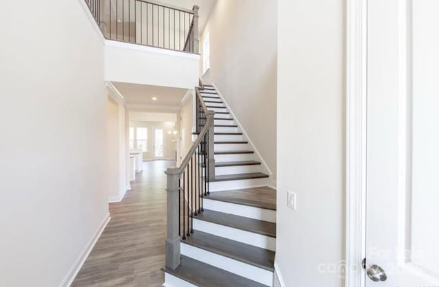 stairs featuring baseboards, a high ceiling, and wood finished floors