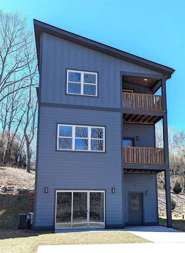 back of house featuring a balcony, central AC unit, and board and batten siding