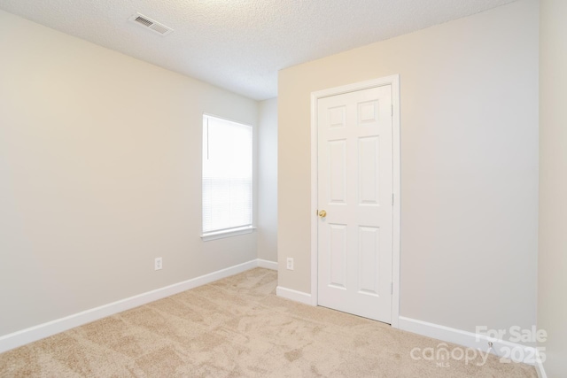 unfurnished bedroom with carpet flooring, baseboards, visible vents, and a textured ceiling