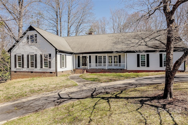 view of front of property with covered porch, a chimney, a front lawn, a shingled roof, and crawl space