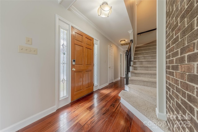 foyer entrance featuring crown molding, baseboards, stairway, dark wood-type flooring, and a wealth of natural light