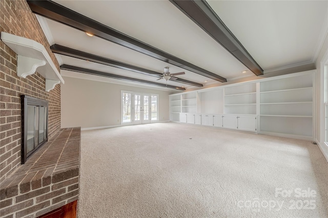 unfurnished living room featuring beamed ceiling, a brick fireplace, a ceiling fan, built in features, and carpet floors