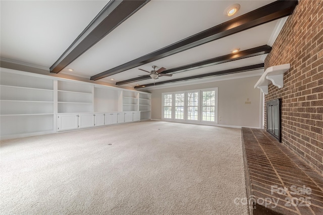 unfurnished living room with crown molding, carpet flooring, brick wall, beamed ceiling, and a fireplace