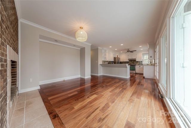 unfurnished living room featuring baseboards, a fireplace, crown molding, and light wood-style flooring