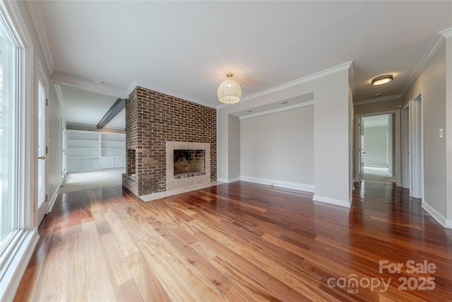 unfurnished living room featuring wood-type flooring, a brick fireplace, ornamental molding, and baseboards