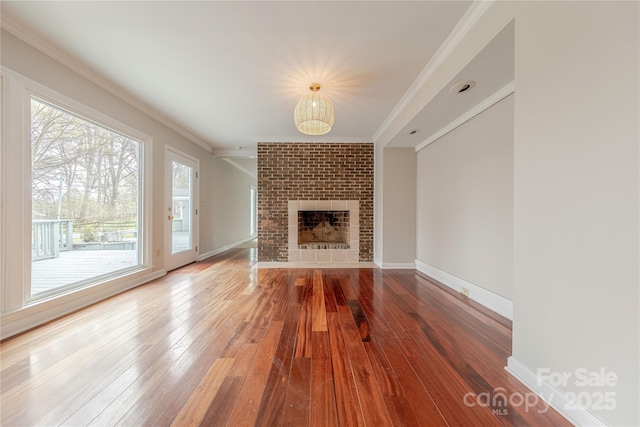 unfurnished living room featuring baseboards, a fireplace, crown molding, and hardwood / wood-style flooring