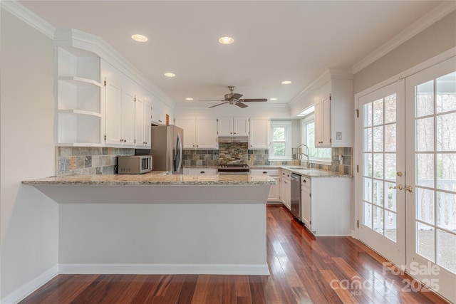 kitchen featuring light stone counters, open shelves, a peninsula, stainless steel appliances, and dark wood-type flooring