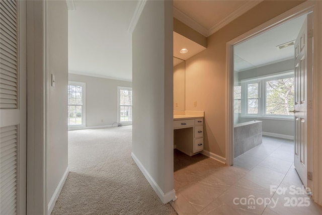 hallway with light carpet, crown molding, and baseboards