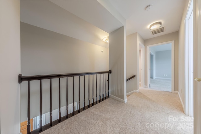 hallway with carpet flooring, an upstairs landing, baseboards, and visible vents