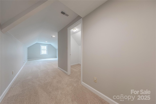 additional living space featuring light colored carpet, visible vents, lofted ceiling, and baseboards