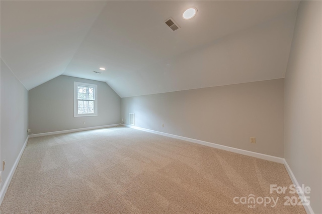 additional living space with vaulted ceiling, baseboards, light colored carpet, and visible vents