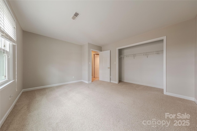 unfurnished bedroom featuring multiple windows, visible vents, baseboards, and carpet flooring