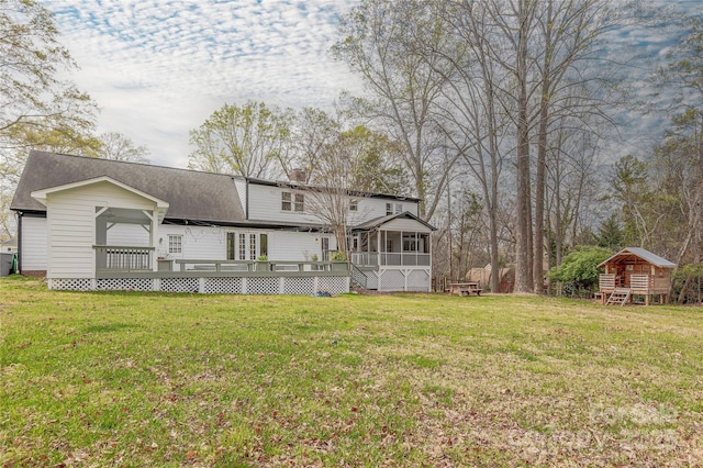 back of property featuring a lawn, a chimney, a shingled roof, and a sunroom
