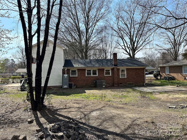 rear view of property featuring cooling unit, brick siding, and a chimney