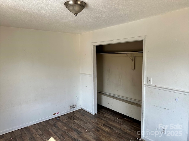 unfurnished bedroom featuring visible vents, wood finished floors, a closet, and a textured ceiling