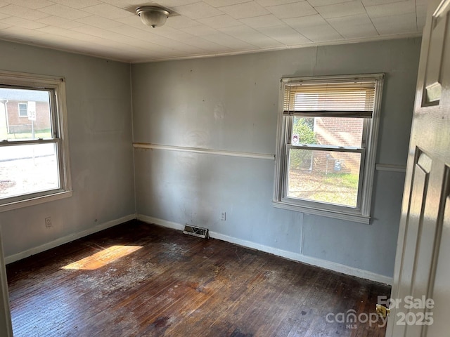 spare room with visible vents, baseboards, and hardwood / wood-style flooring