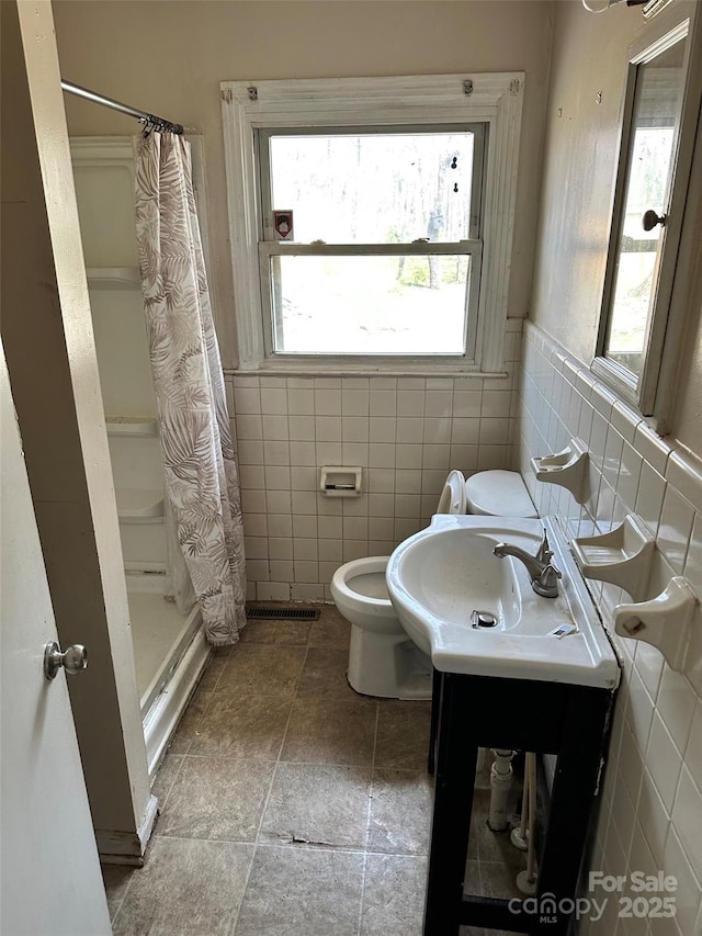 full bath featuring a stall shower, toilet, and tile walls