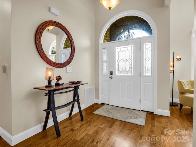 foyer with wood finished floors, visible vents, and baseboards