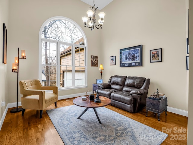 living room with a chandelier, baseboards, and wood finished floors