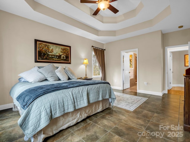 bedroom with baseboards, a tray ceiling, and a ceiling fan