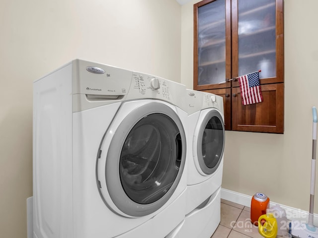 washroom featuring baseboards, light tile patterned flooring, washing machine and dryer, and laundry area