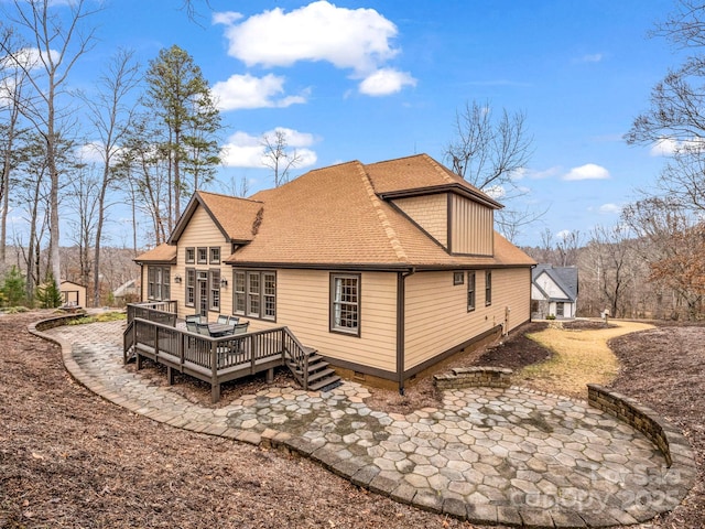 back of house featuring a wooden deck, an outdoor structure, and a shingled roof