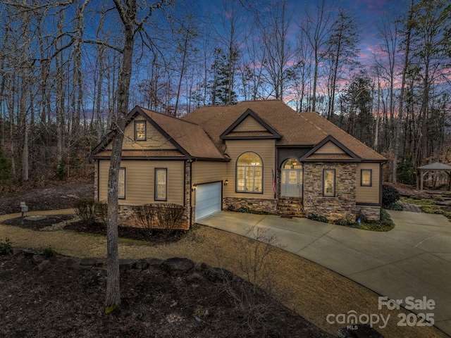 view of front of home featuring a garage, stone siding, driveway, and a shingled roof