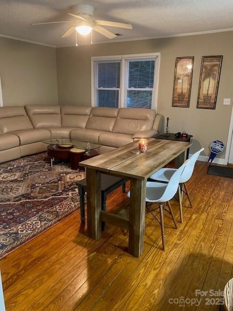 living room with a textured ceiling, crown molding, wood finished floors, and ceiling fan