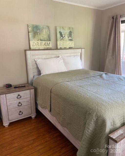 bedroom with ornamental molding and dark wood-style flooring